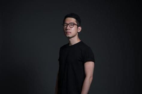 Nathan Law wearing a black tshirt standing against a dark background